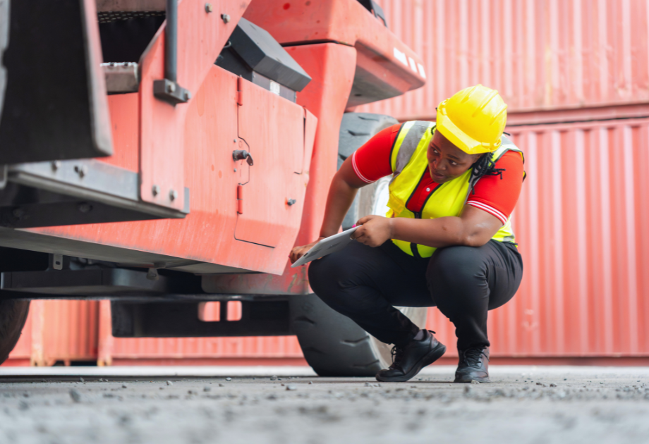 woman in a hard hat and vest inspecting a red truck